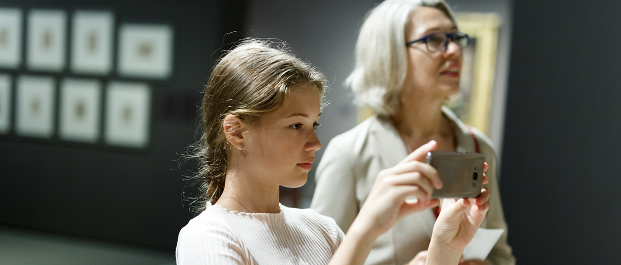 Mitmachen für Kinder , Eltern und Erziehungsberechtigte. Mädchen fotografiert mit ihrem Handy in einer Ausstellung